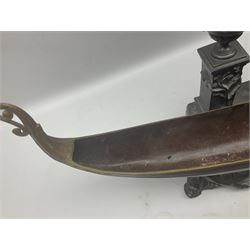 Bronzed and pewter figure group depicting a gentleman stood holding an oar behind his long boat beside a twin handled urn, raised on ornate base with whimsical grotesque fish supports, H52cm