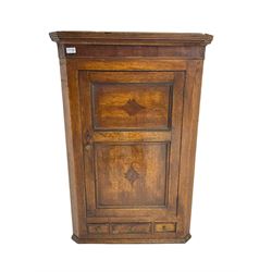 George III oak and mahogany banded wall hanging corner cupboard, reeded cornice over panelled door with inlaid detail enclosing three shelves with shaped fronts, fitted with three small crossbanded drawers to base
