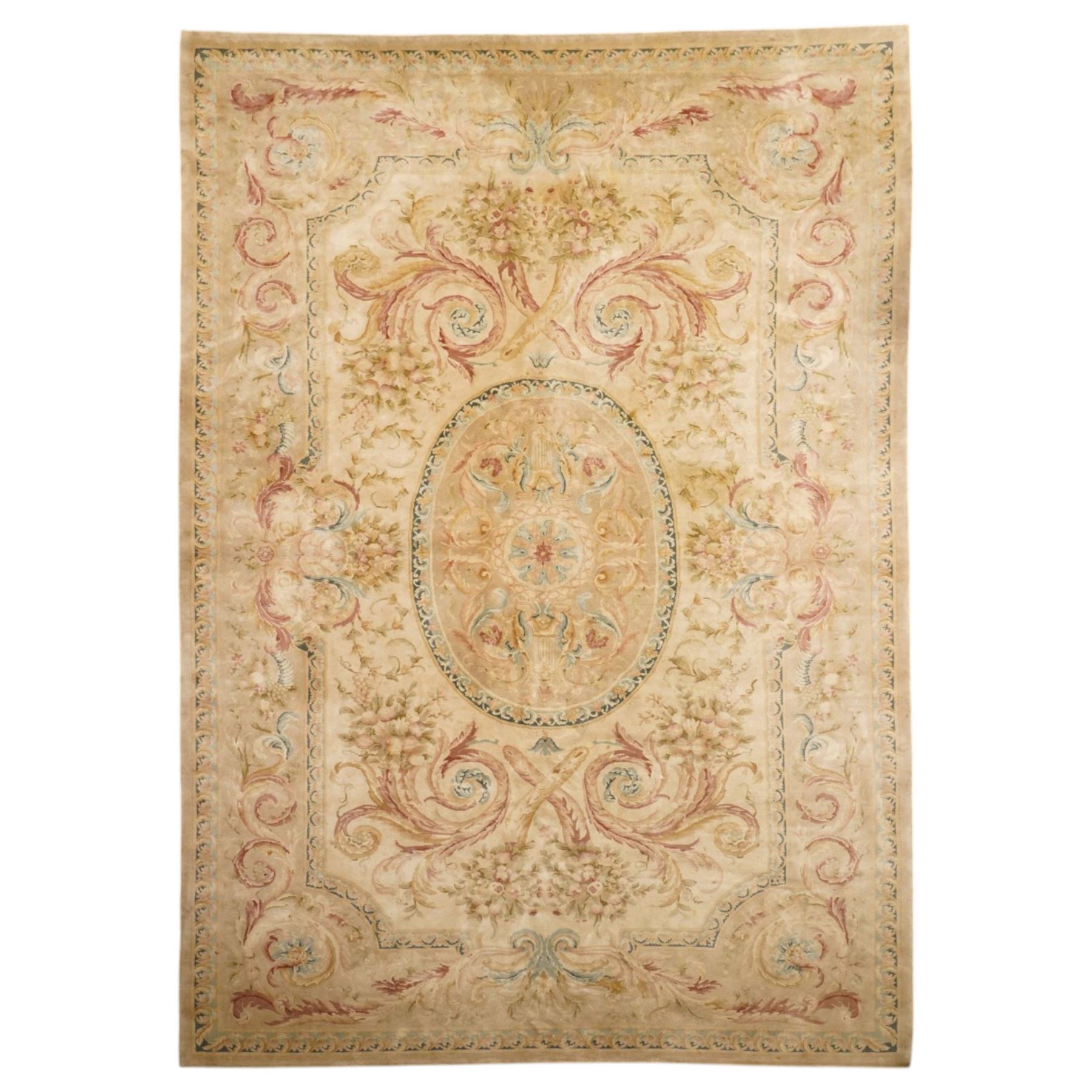 Large Aubusson design flatweave carpet, cream ground centred by oval medallion decorated with scrolling acanthus leaves and flowerheads, surrounded by floral sprays, foliate scrolls and rocaille motifs in muted pink, blue and gold tones, enclosed by conforming foliate border