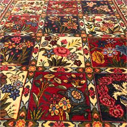 Central Persian Bakhtiar hand-knotted runner, field arranged with a garden panel  design of floral sprays and foliage within a flowerhead and vine border, in tones of crimson, ivory, and indigo with cotton fringe ends 