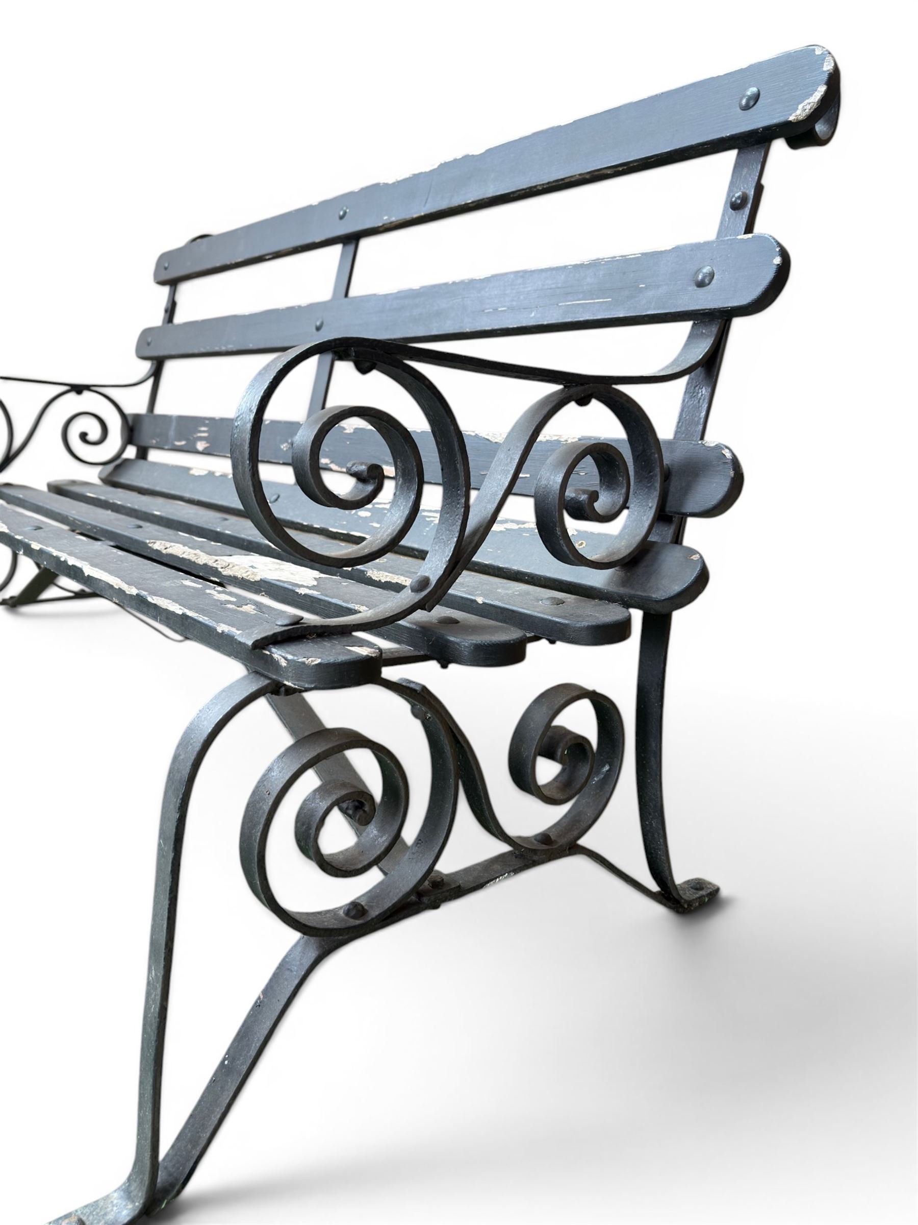 Coalbrookdale - rare pair of wrought iron and slatted wood garden benches, the twin wrought iron strapwork bench-ends formed of four scrolls over splayed feet, number 77 in the Coalbrookdale Castings Catalogue (see illustration)