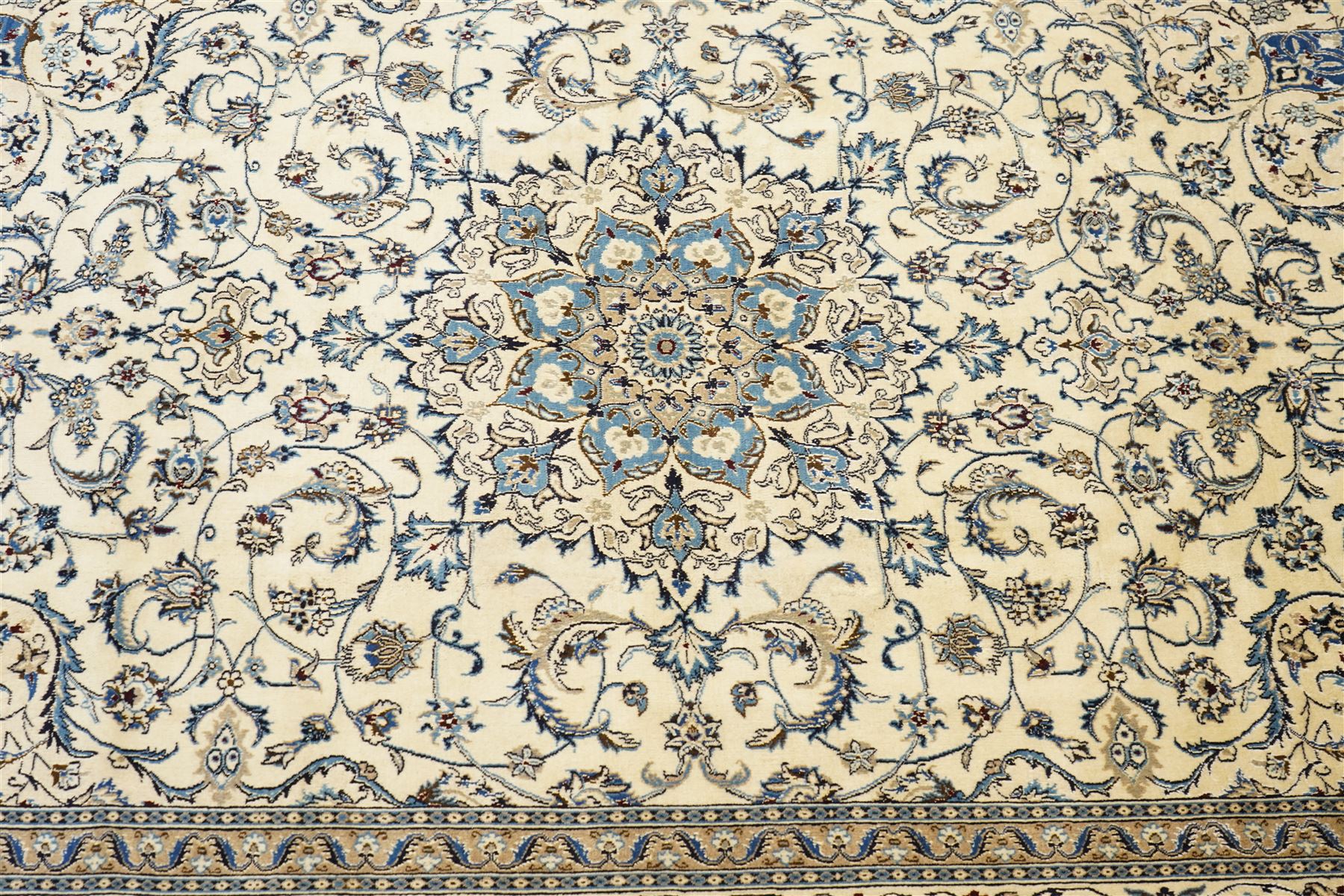 Central Persian Nain hand-knotted carpet, ivory field with central radiating medallion, issuing an all-over design of scrolling vines, palmettes, and delicate floral sprays with conforming spandrels, enclosed by a foliate border, framed by multiple guard stripes, with cotton fringe ends 