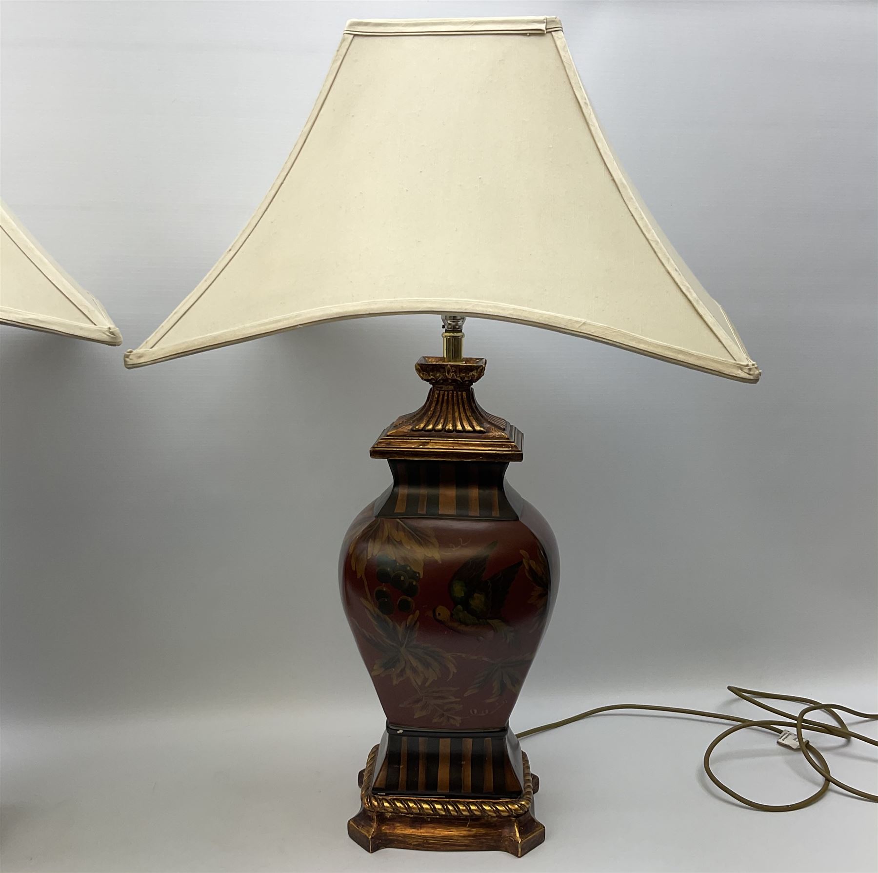 Pair Oriental table lamps decorated with birds in a tree with fruit, on a red ground with a gilded base together with cream lampshades H57cm, without lampshade. 