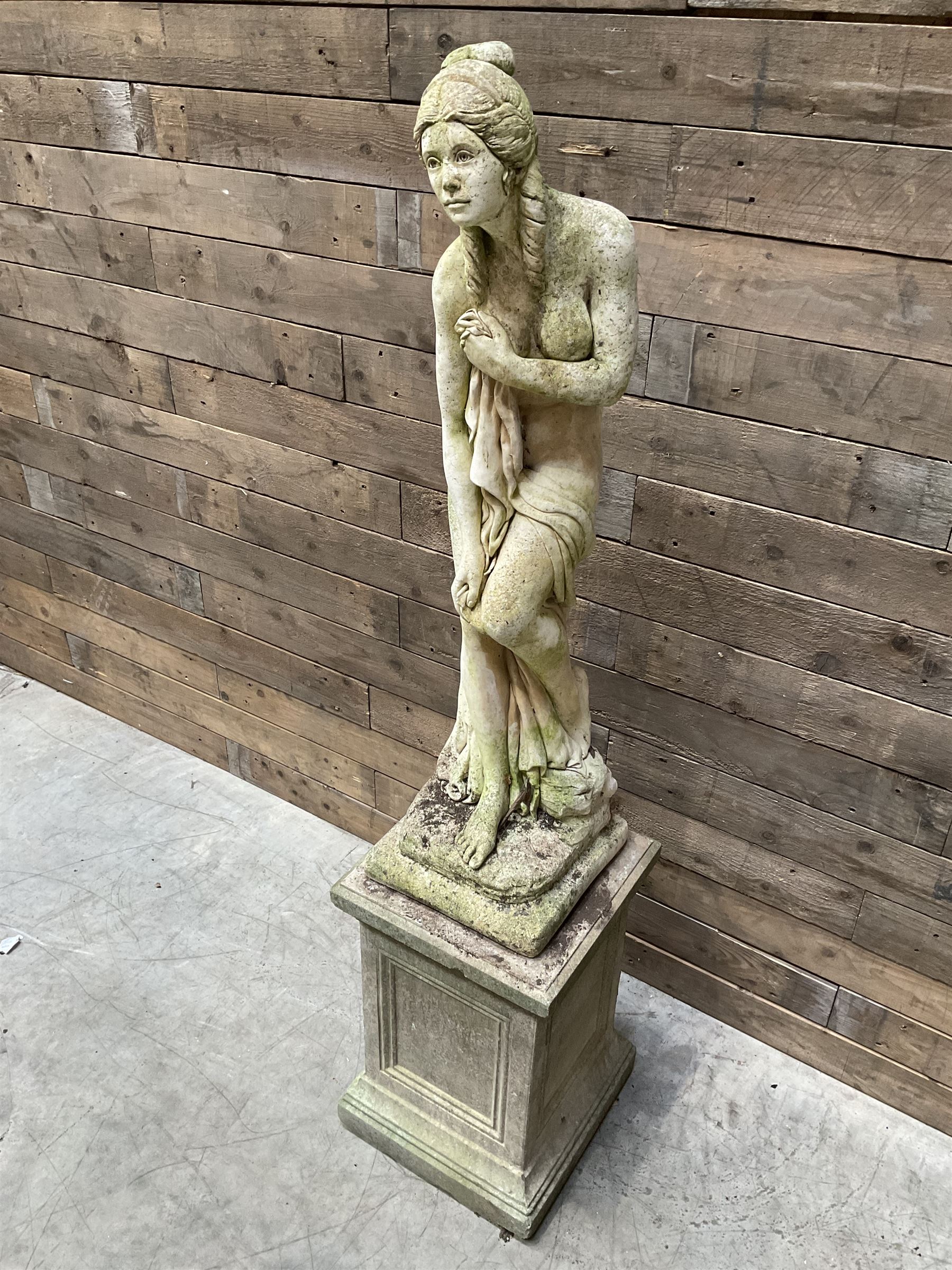 Cast stone garden figure of a bathing lady, raised on square plinth