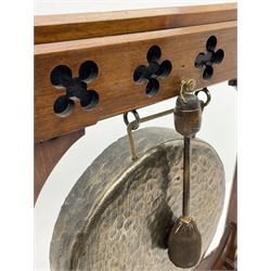 Late Victorian Aesthetic Movement walnut and ebonised dinner gong, the trestle frame with pierced quatrefoil motifs supporting circular hammered bronze gong, splayed angular supports