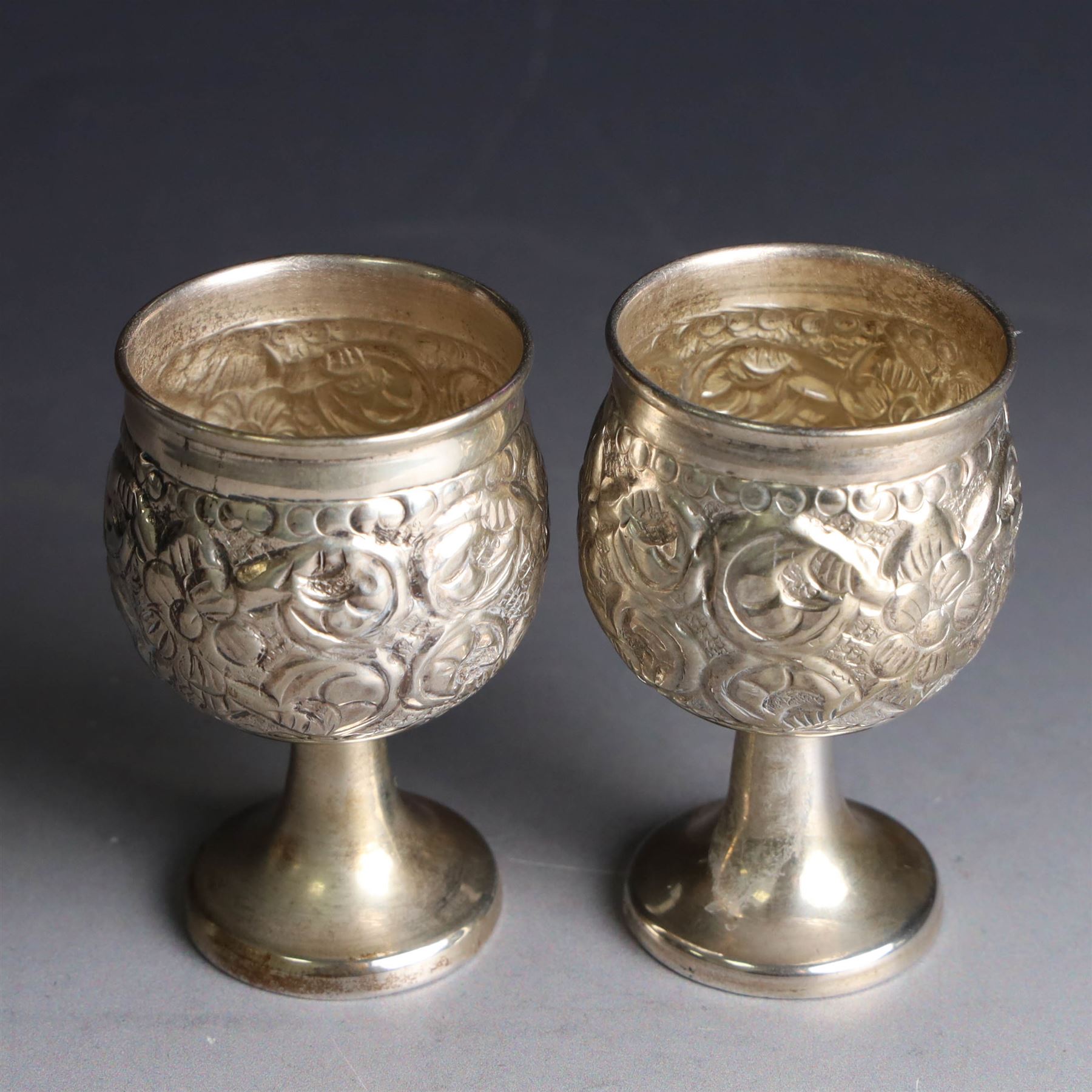 Pair of miniature Indian silver goblets, with embossed floral and foliate decoration, H6.5cm