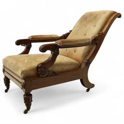 William IV mahogany gentleman's library reclining armchair, leather button upholstered and brass-studded back and seat, above leather-covered arms terminating with carved roundels and foliate scroll-carved ends, underside with brass mechanical trigger reclining lever, the apron with retractable foot rest, supported on lappet carved and turned legs with brass castors, circa 1835
