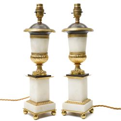 Pair of early 20th-century Neoclassical lamp bases in gilt bronze and alabaster, each decorated with classical figural reliefs celebrating the arts, each of baluster form, the alabaster bodies applied with finely cast gilt-bronze scenes including a seated painter at an easel, a sculptor at work, and allegorical female figures with musical  and theatrical motifs, mounted on square alabaster plinths with gilt-bronze borders and raised on bun feet, the domed shoulders enriched with laurel-leaf mouldings, H42cm 