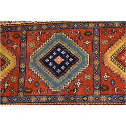 Caucasian Kazak vermillion ground rug, the sectioned field decorated with three geometric lozenge medallions surrounded by stylised plant and animal motifs, the multiple guard bands with repeating geometric design