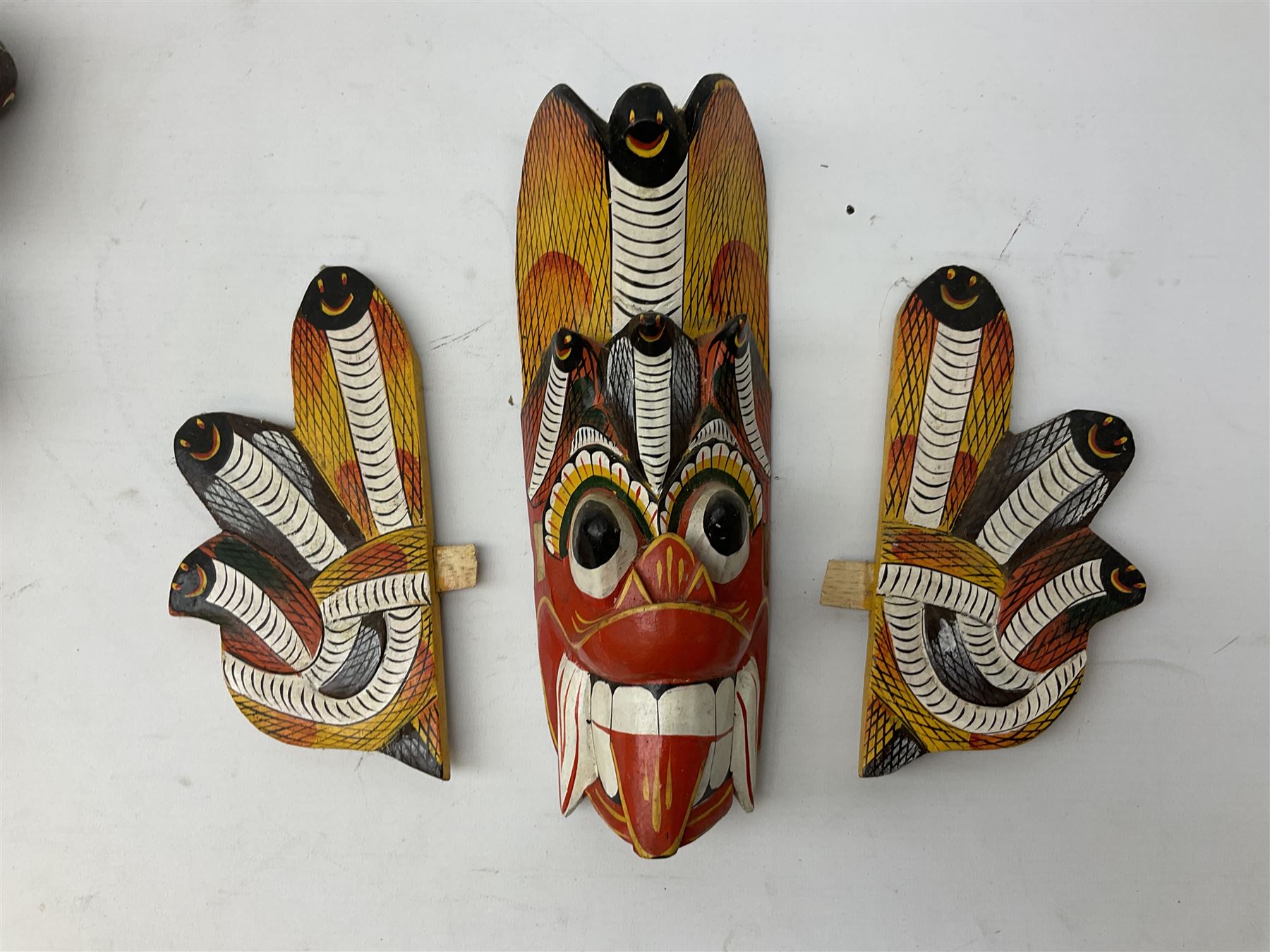 Sri Lankan Cobra mask depicting the demon Naga Raksha, together with a smaller example, largest H46cm