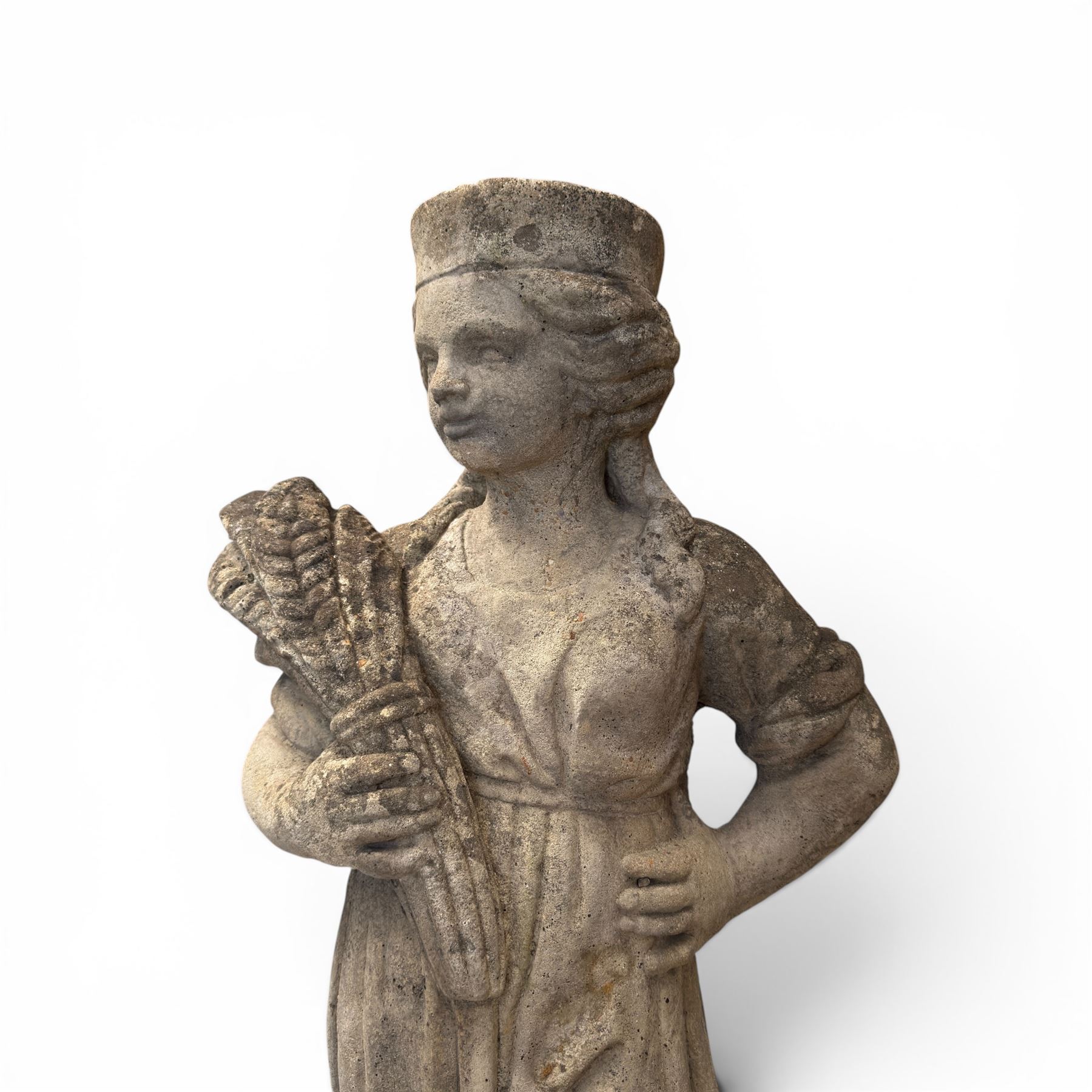 Lucas Stone - pair of cast stone garden figures, modelled as young female figures holding wheat sheafs and baskets of flowers, each on square bases, weathered finish, makers mark stamped to base