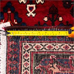 Central Persian Joshagan hand-knotted rug, madder-red field with central stepped lozenge medallion enclosed by angular spandrels, field decorated with repeating stylized geometric floral motifs and small diamond devices enclosed by a dark border of geometric ornament between multiple guard stripes, with cotton fringe ends  