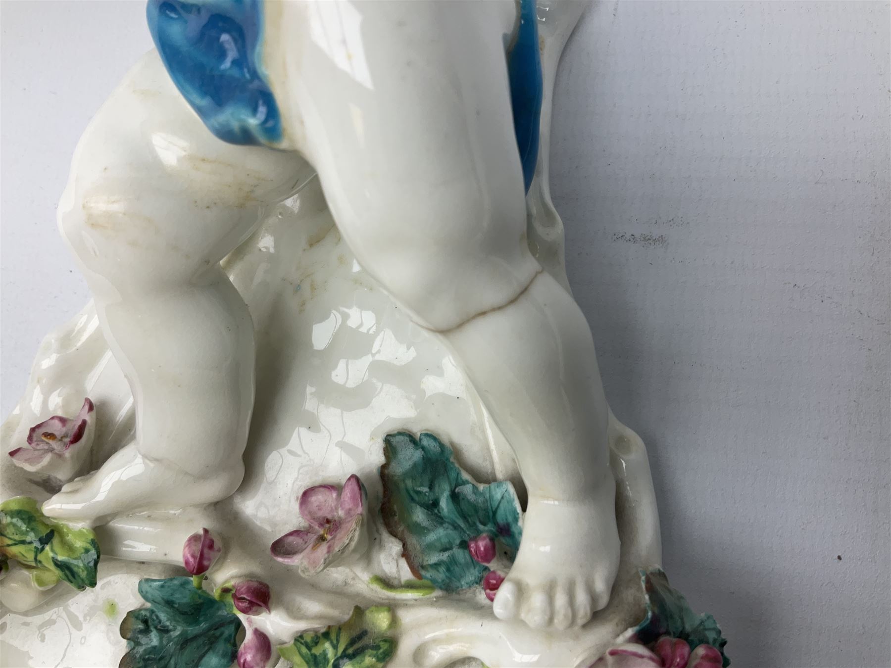 Victorian wall pocket by Moore Brothers retailed by T.Goode modelled as a semi nude white glaze cherub with turquoise ribbon, with encrusted floral decoration, the reverse stamped ‘T.Goode & Co.’, H32cm