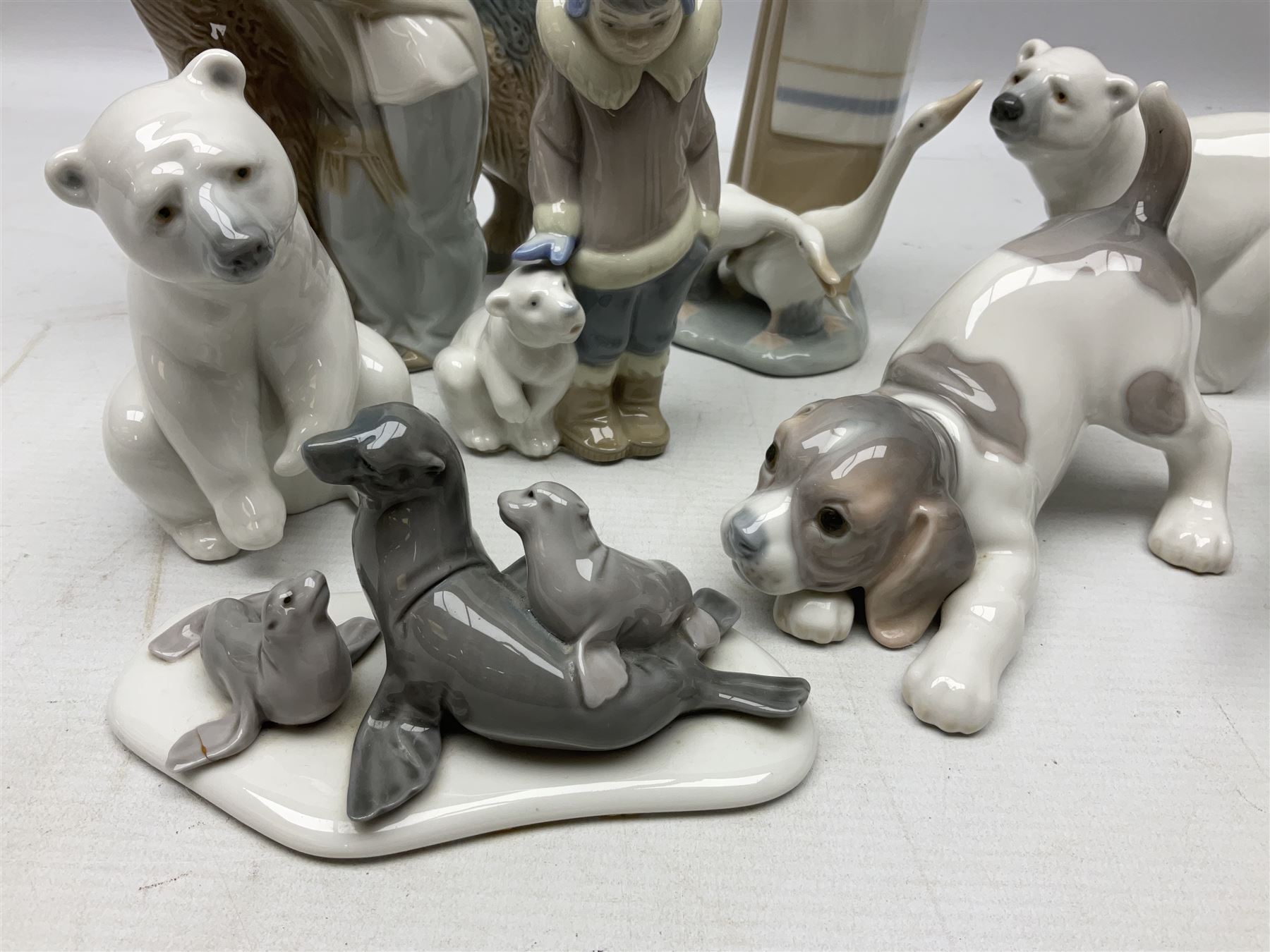 Seven Lladro figures, comprising Playful Puppy no 9135, Platero and Marcelino/Boy Hugging Donkey no 1181, Mini Seal Family no 5318, Attentive Polar Bear no 1207, Seated Polar Bear no1209, Eskimo Boy with Pet no 5238 and Girl with Geese no 1035, together with Nao goose