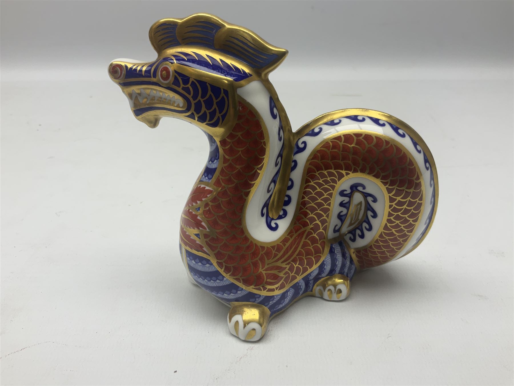 Three Royal Crown Derby paperweights, comprising Macaque, with gold stopper and original box, Monkey and Baby, with silver stopper and original box and Dragon with silver stopper, all with printed mark beneath  