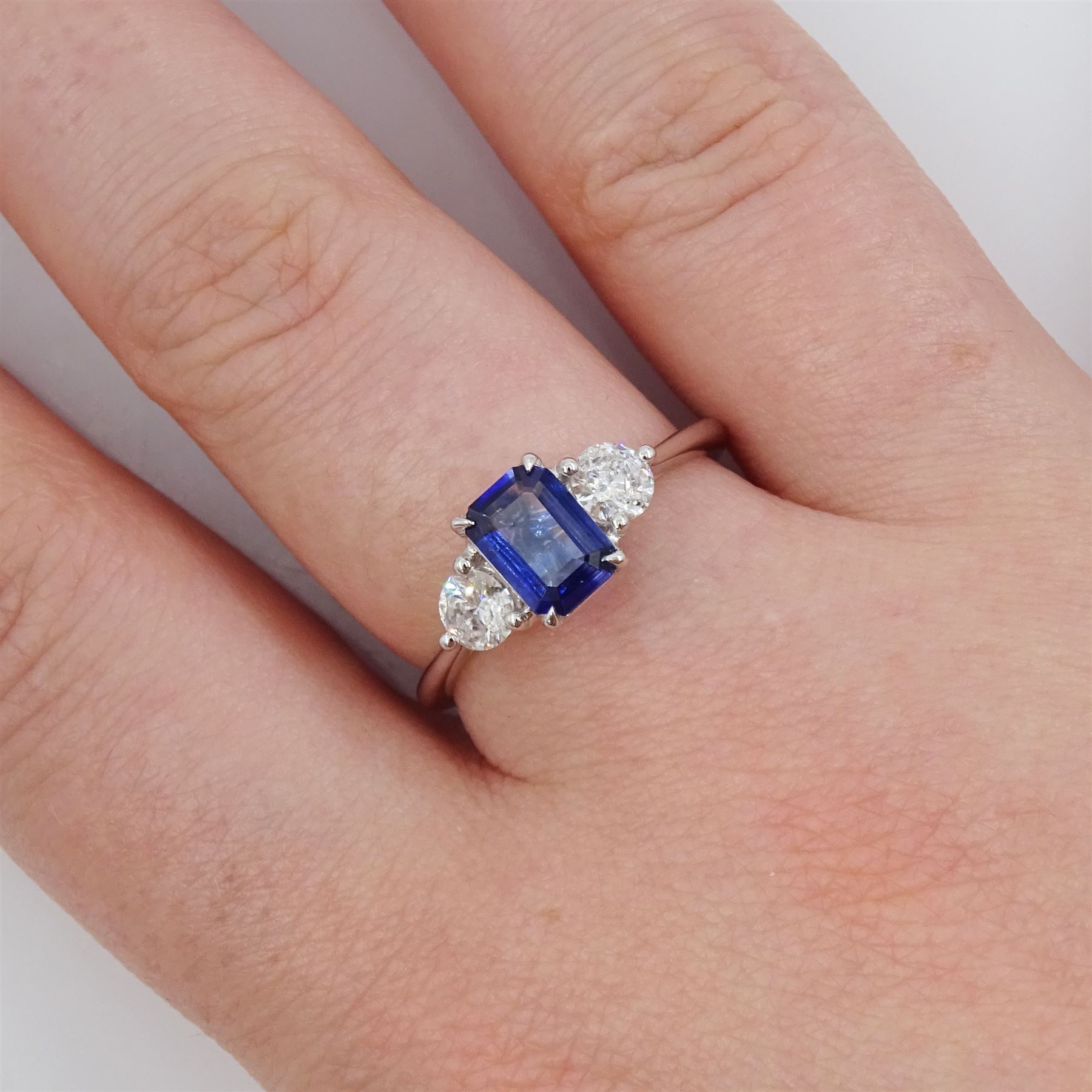 Platinum sapphire and diamond three stone ring, single emerald cut sapphire of approx 0.70 carat, either side set with two round brilliant cut diamonds, hallmarked, total diamond weight approx 0.50 carat
