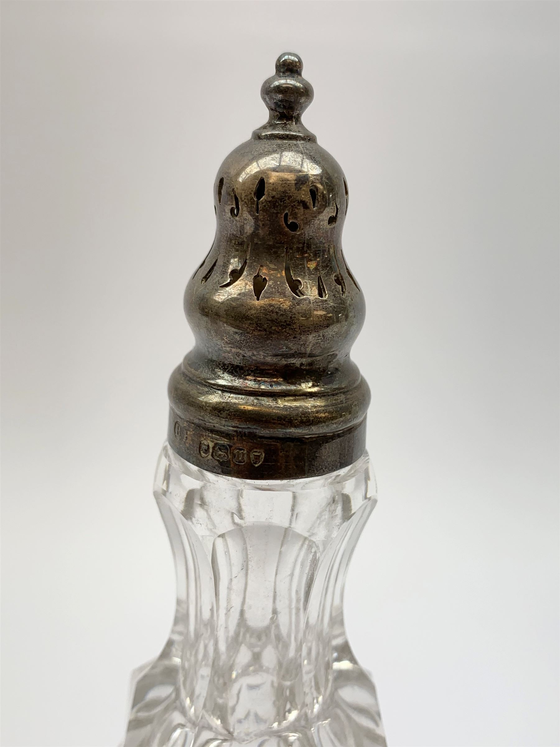 A group of Victorian glass condiment bottles, to include a set of four bottles and jar with cut decoration, one bottle with pierced silver domed top, another bottle with silver gilt spoon top, and jar with silver domed hinged cover, all hallmarked Robert Harper, London 1868. (8). 
