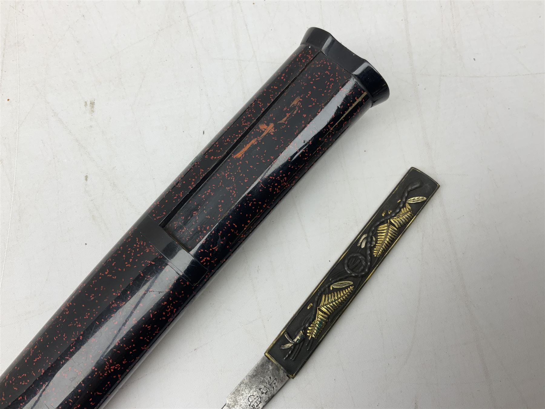 Japanese Tanto with 28.5cm steel blade and cord bound grip; in red spotted black lacquer saya containing a kogai knife with etched characters to the blade and ornate fern leaf and snake handle