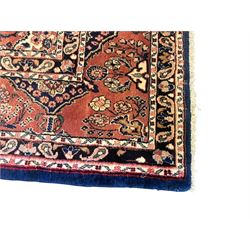 Persian Herati design indigo and red ground carpet, decorated with floral motifs, arched border