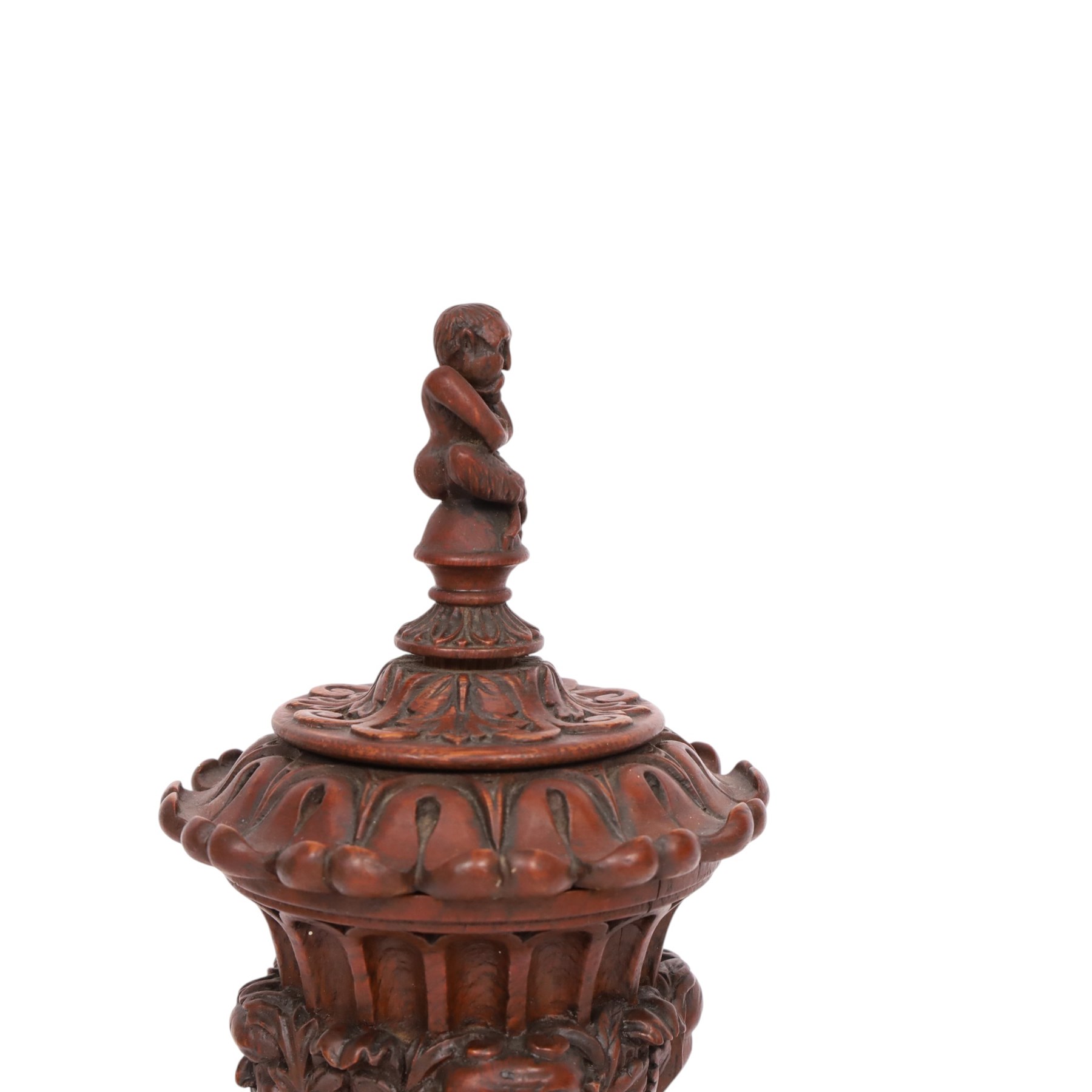 Carved wooden urn. decorated in relief with carved faces within foliage, with a Satyr finial, H25cm 
