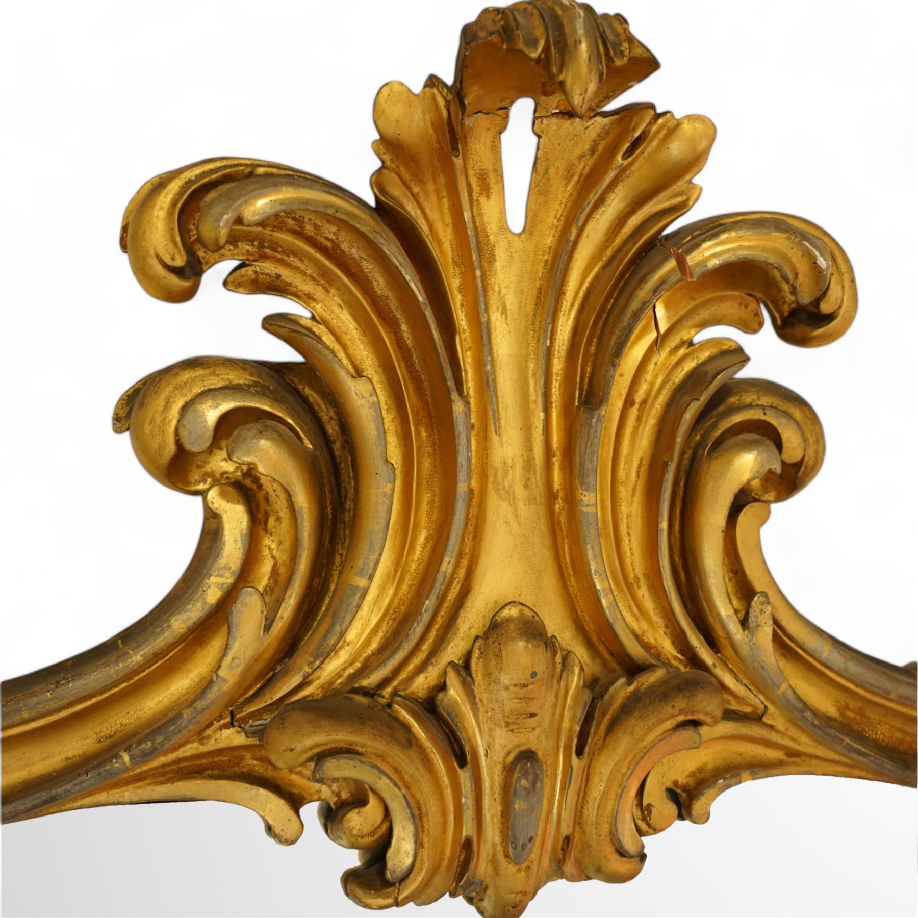Large Victorian gilt wood overmantle mirror, shaped cresting rail with curled acanthus leaf pediment, the corners decorated with foliate C-scrolls and flower heads, curled foliage lower corner brackets, plain mirror plate 