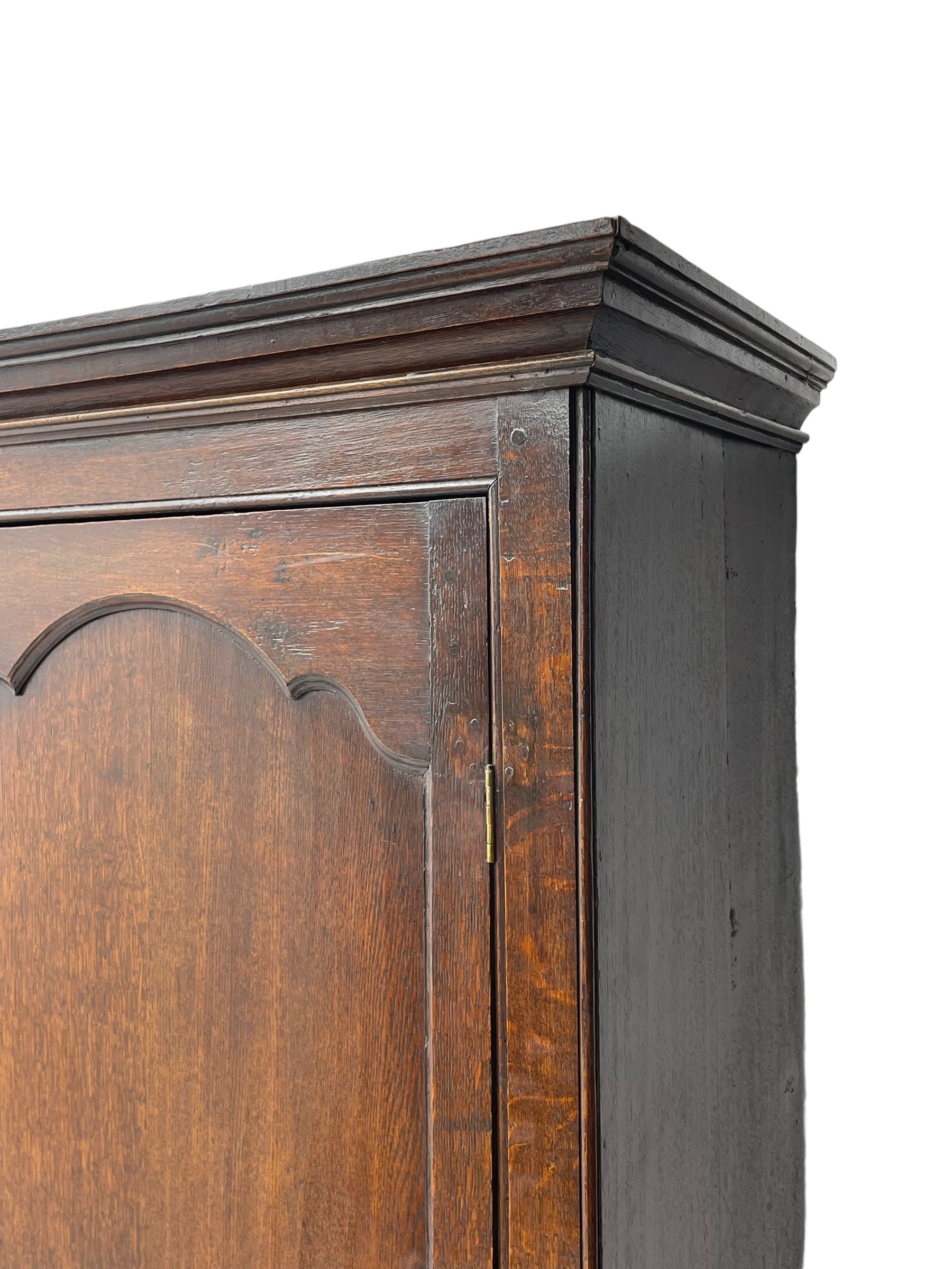 George III oak livery cupboard, projecting moulded cornice over two panelled doors, the upper panels within stepped ogee and arched moulded frame, the interior fitted with a single row of wooden hooks, two short and one long drawers, on bracket and return skirted base 