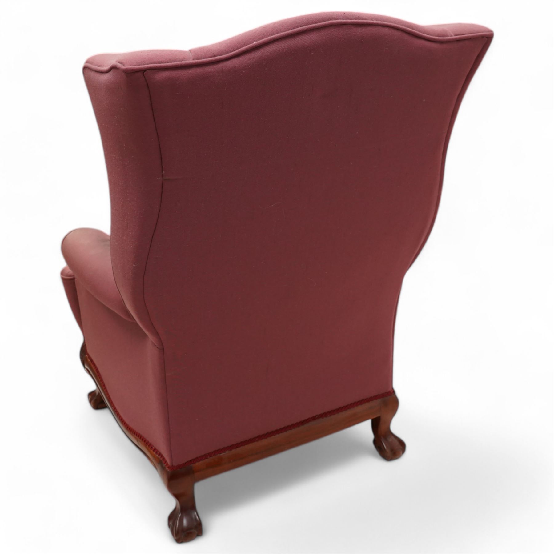 Georgian design mahogany framed wingback armchair, upholstered in rouge fabric, on ball and claw feet with foliate cartouche decoration 