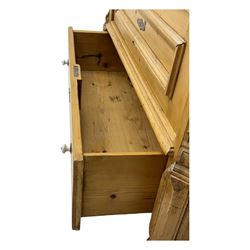 Late 19th century Continental pine vitrine, shaped and moulded arched cornice over a single glazed door enclosing adjustable shelves, flanked by carved pilasters with foliate and geometric motifs, fitted with single moulded drawer, raised on compressed bun feet