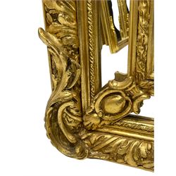 Large Italian Baroque design gilt wall mirror, the shell pediment over circular panel depicting classical female flute player with dancing putto within a tree landscape, the stepped arched upper frame surmounted by musical instrument playing putto and trailing flower heads, central bevelled mirror plate surrounded by plain segmented mirror plates, acanthus leaf moulded outer frame and foliate moulded inner slip