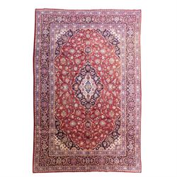 Central Persian Kashan hand-knotted carpet, madder red field with a central cusped medalli...