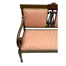 Edwardian inlaid mahogany two-seat settee or hall bench, the cresting rail inlaid with satinwood banding and boxwood stringing, central panel inlaid with scrolled leafy branches over pierced and carved lyre back, upholstered in peach fabric with repeating pattern, scrolled down sweeping arms, on square tapering supports with spade feet 
