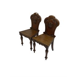 Pair Victorian oak hall chairs, scallop shaped back with carved scrolls and central shield moulding, panel seat over shaped frieze rail, raised on turned supports