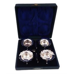 Set of four Edwardian silver open salts, of circular form, each with later personal engraving to scalloped rim and upon three pad feet, together with four matching silver salt spoons, hallmarked James Deakin & Sons, Sheffield 1909, in velvet and silk lined fitted case     