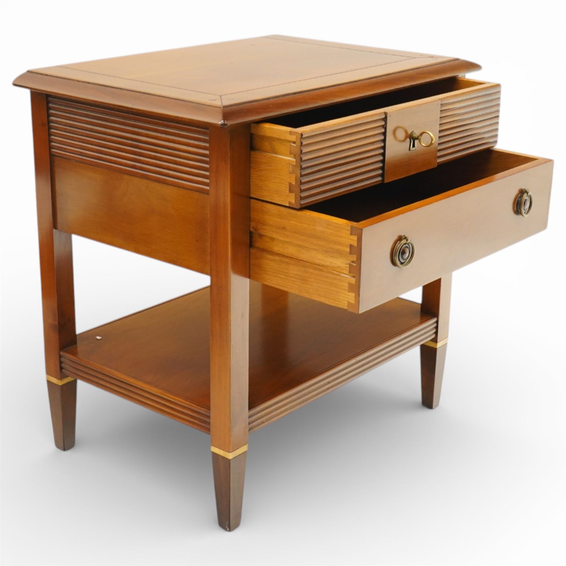 Brigitte Forestier - pair of cherry wood bedside cabinets, moulded rectangular top above two drawers, the top drawer with reeded panels flanking a brass circular pull, the lower drawer with two brass pulls, on square tapering supports united by a full length undertier