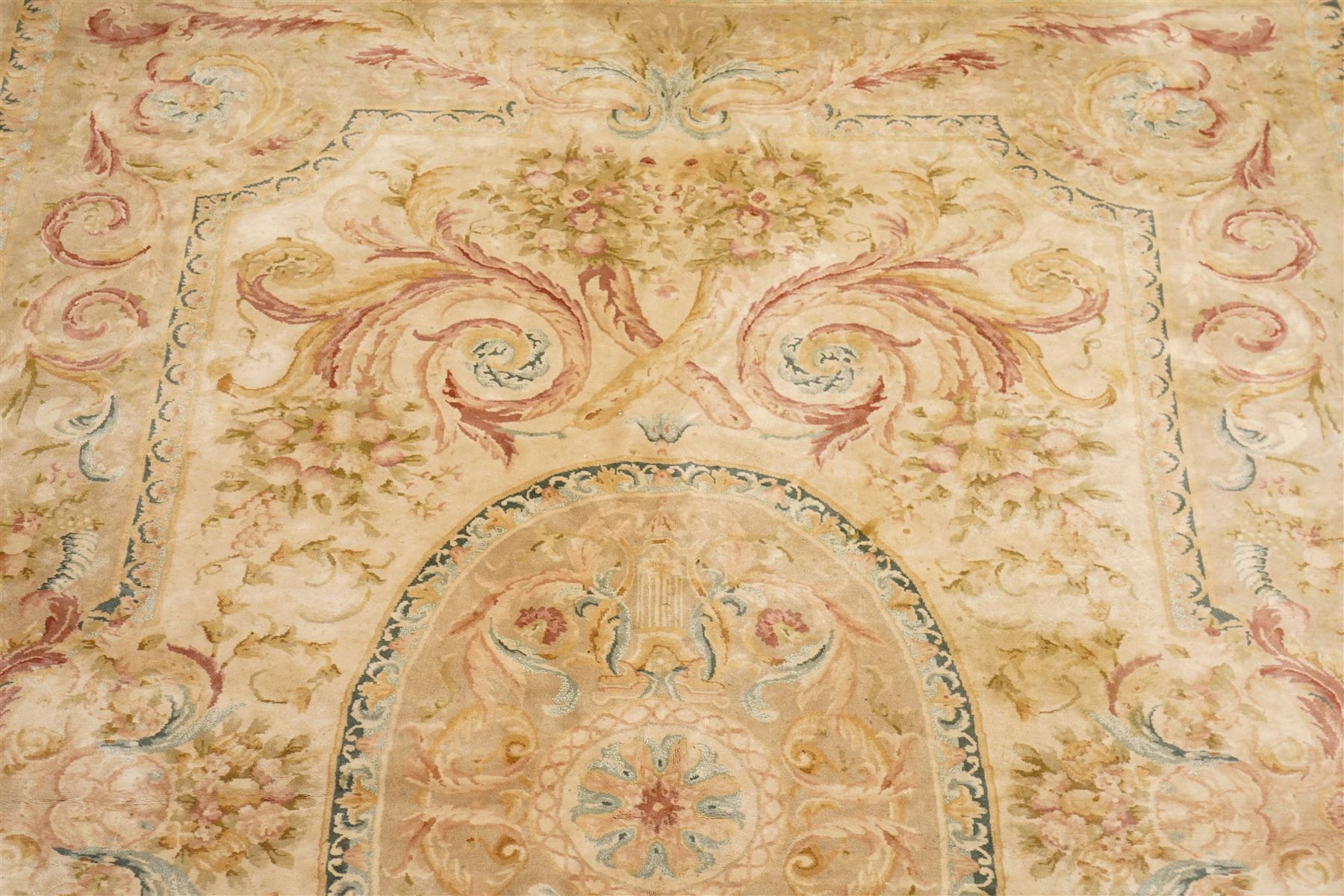 Large Aubusson design flatweave carpet, cream ground centred by oval medallion decorated with scrolling acanthus leaves and flowerheads, surrounded by floral sprays, foliate scrolls and rocaille motifs in muted pink, blue and gold tones, enclosed by conforming foliate border
