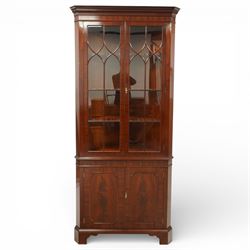 William Tillman - Early 20th century mahogany corner cabinet, the projecting moulded cornice with dentil detail over a glazed upper section enclosed by a pair of astragal glazed doors with Gothic arched tracery, the interior fitted with shaped shelves, above a moulded waist and a lower cupboard enclosed by two panelled doors with shaped fielded panels, raised on bracket feet