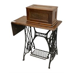 Singer - early 20th century cast iron treadle sewing machine, with hand crank wheel and oak work surface, the machine decorated with gilt foliate detail, complete with rectangular wooden cover and folding extension leaf