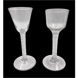 Two 18th century drinking glasses, the first example with ogee shaped bowl upon a double series opaque twist stem and conical foot, the second with round funnel bowl upon a single series air twist stem and conical foot, each approximately H15cm