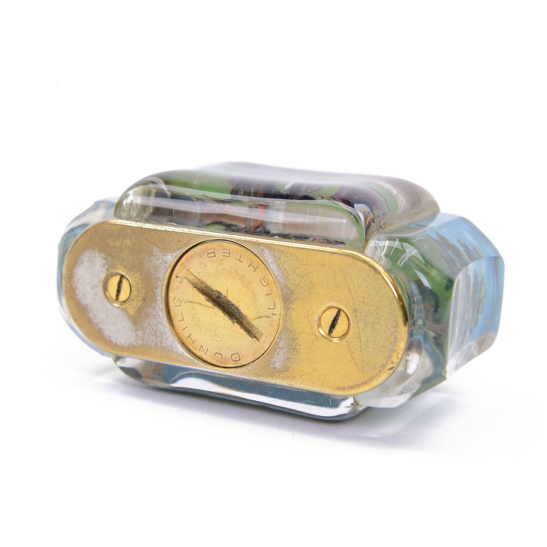 Rare one off special commission Dunhill Sporting Horse Racing half-giant 'Aquarium' table lighter, circa 1955, the lucite panelled body engraved in reverse intaglio technique and hand-painted with Nicholas Nickleby in action, winner of the Royal Hunt Cup, Ascot June 1955, the reverse with jockey Willie Snaith mounted upon Nicholas Nickleby, the gold plated top with arm stamped Dunhill Reg. No 737418, the base stamped DUNHILL LIGHTER, H7.5cm W10cm D5cm

Provenance:
Commissioned by the owner of Nicholas Nickleby, the lighter was gifted to Colin Hetherton, a young veterinary surgeon whose intervention saved Nickleby from certain retirement. Hetherton’s expert care and persistence brought the horse back to full health, culminating in a win that stunned the Ascot crowd.