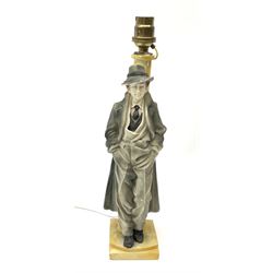 A moulded resin table lamp, modelled as a man in 1940s dress leaning against a lamp post, including fitting H32cm.