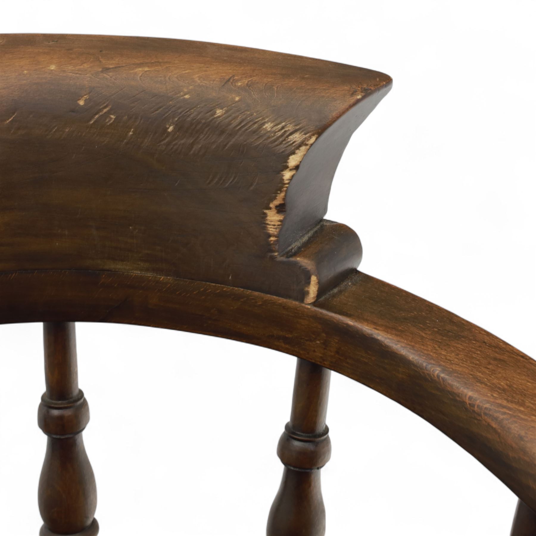 Early 20th century smokers bow armchair, shaped and curved top rail over turned spindles and open arms with rounded terminals, shaped elm seat on turned supports