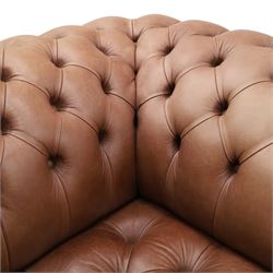 Distinctive Chesterfield - full buttoned tan brown leather sofa, deep buttoned back, seat and arms, raised on dark stained supports terminating in brass castors 