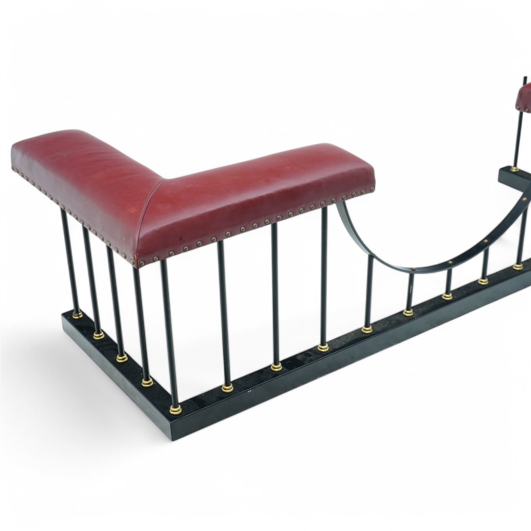 Wrought metal and brass fire fender, L-shaped corner seats upholstered in burgundy fabric with stud bands, dished centre on balustrade and plain curb  