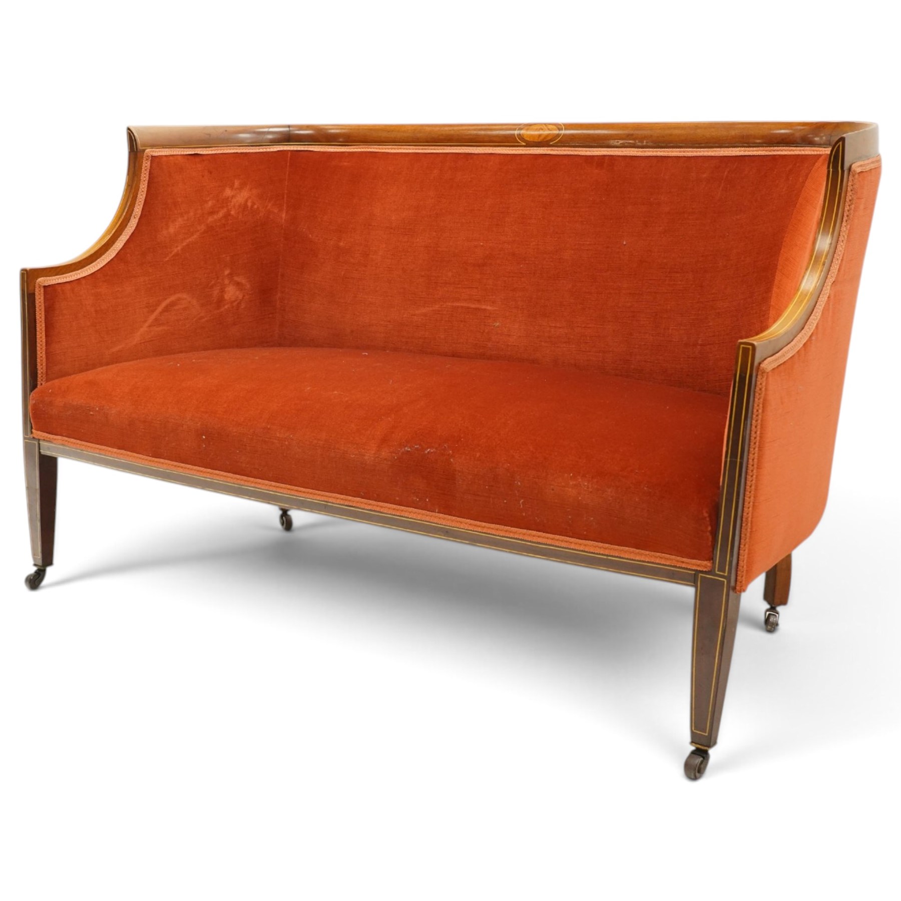 Edwardian inlaid mahogany tub two seater settee, traditional shape with satinwood stringing, upholstered in crimson fabric with sprung seat, on square tapering supports with castors