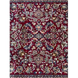 Central Persian Yazd hand-knotted rug, madder red field with scrolling vines, palmettes, and rosettes around a cusped lozenge medallion within a blue ground border of palmettes and flowerheads, 366cm x 250cm