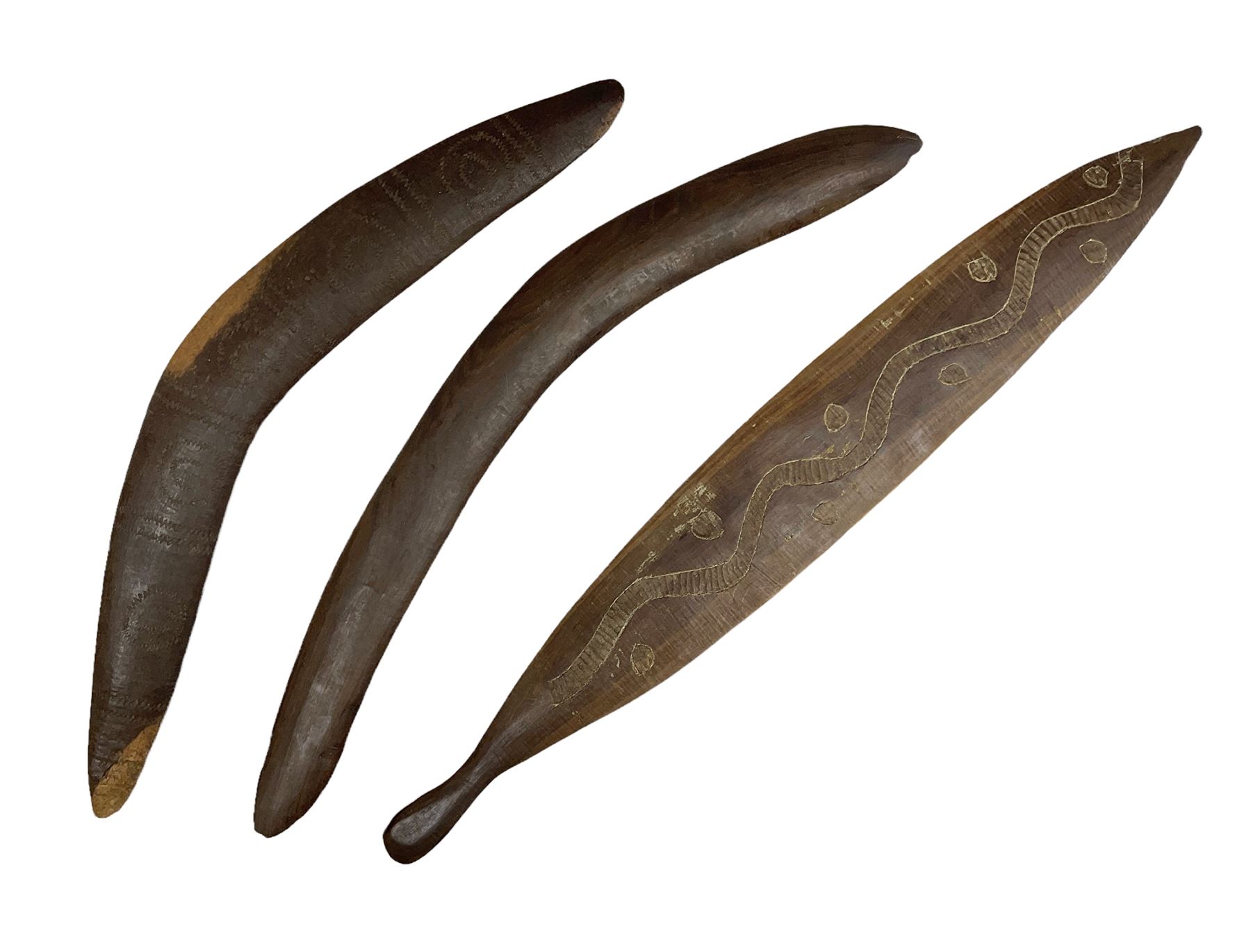 Australian aboriginal woomera spear thrower incised/carved with a wavy line and dots L69cm; and two boomerangs, one with carved geometric decoration (3)