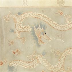 Chinese wool rug, the pale grey central field decorated with two stylised dragons, flaming pearls and cloud scrolls, within a cream border of shou medallions and geometric motifs, with cotton fringe ends