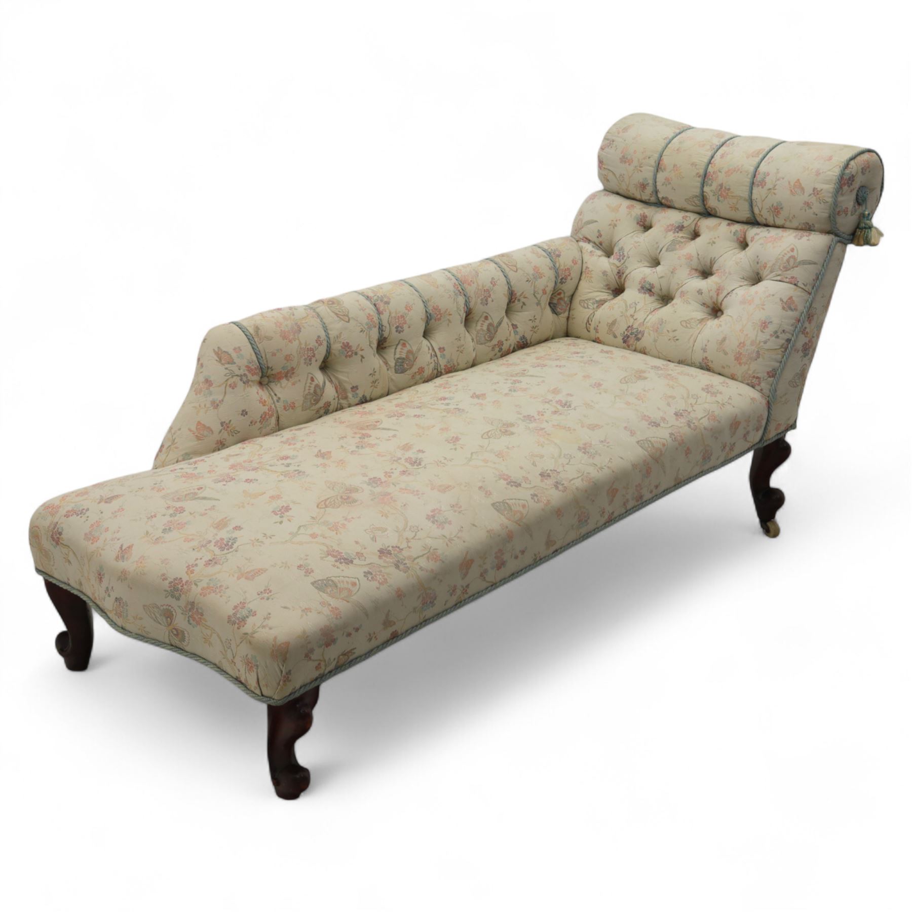 Late 19th century upholstered chaise longue, the gently scrolled headrest above a buttoned back and sprung seat, upholstered in a floral patterned fabric, raised on cabriole mahogany supports with ceramic castors