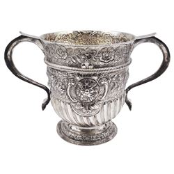 George I silver Britannia standard twin handled cup, the urn shaped bowl with twin scroll handles, later embossed part fluting, rope girdle and foliate decoration, and gilt interior, upon a circular stepped foot, hallmarked Matthew Lofthouse, London 1721, H16.5cm, approximate weight 19.75 ozt (614.2 grams)
