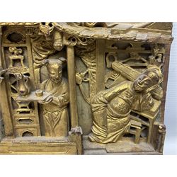 Two carved oriental wall hangings, the first example gilded depicting a temple and garden scene, the second figures in a garden, L49cm